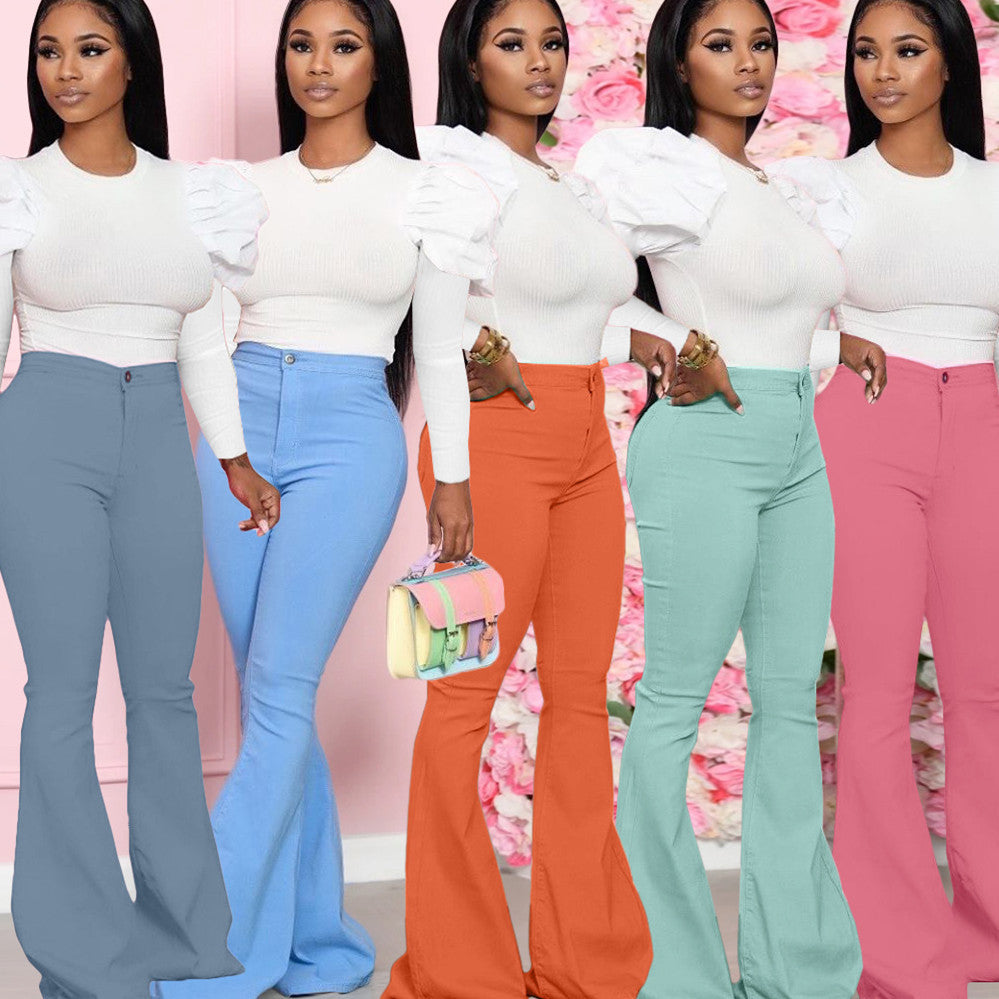 Five women wearing white tops and colorful flared pants against a floral background