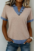 Woman wearing a beige and blue top with denim accents on a plain background