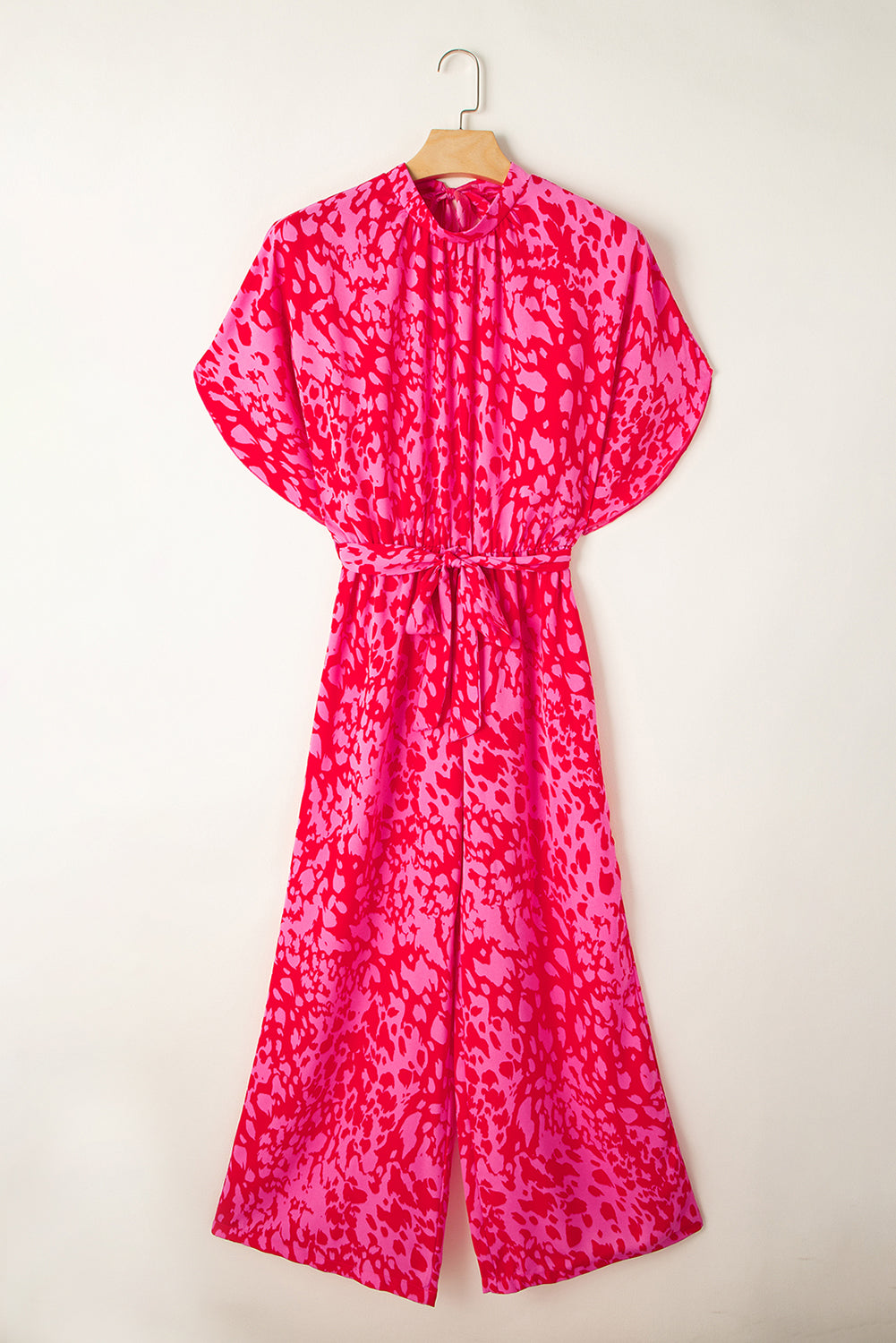 Pink patterned jumpsuit back on a hanger against a white background