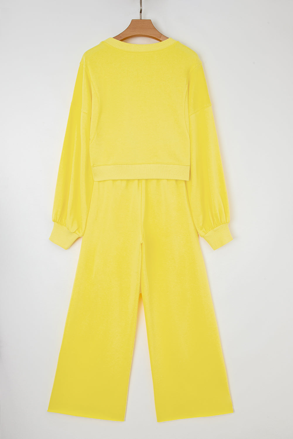 Yellow outfit on a hanger against a white background