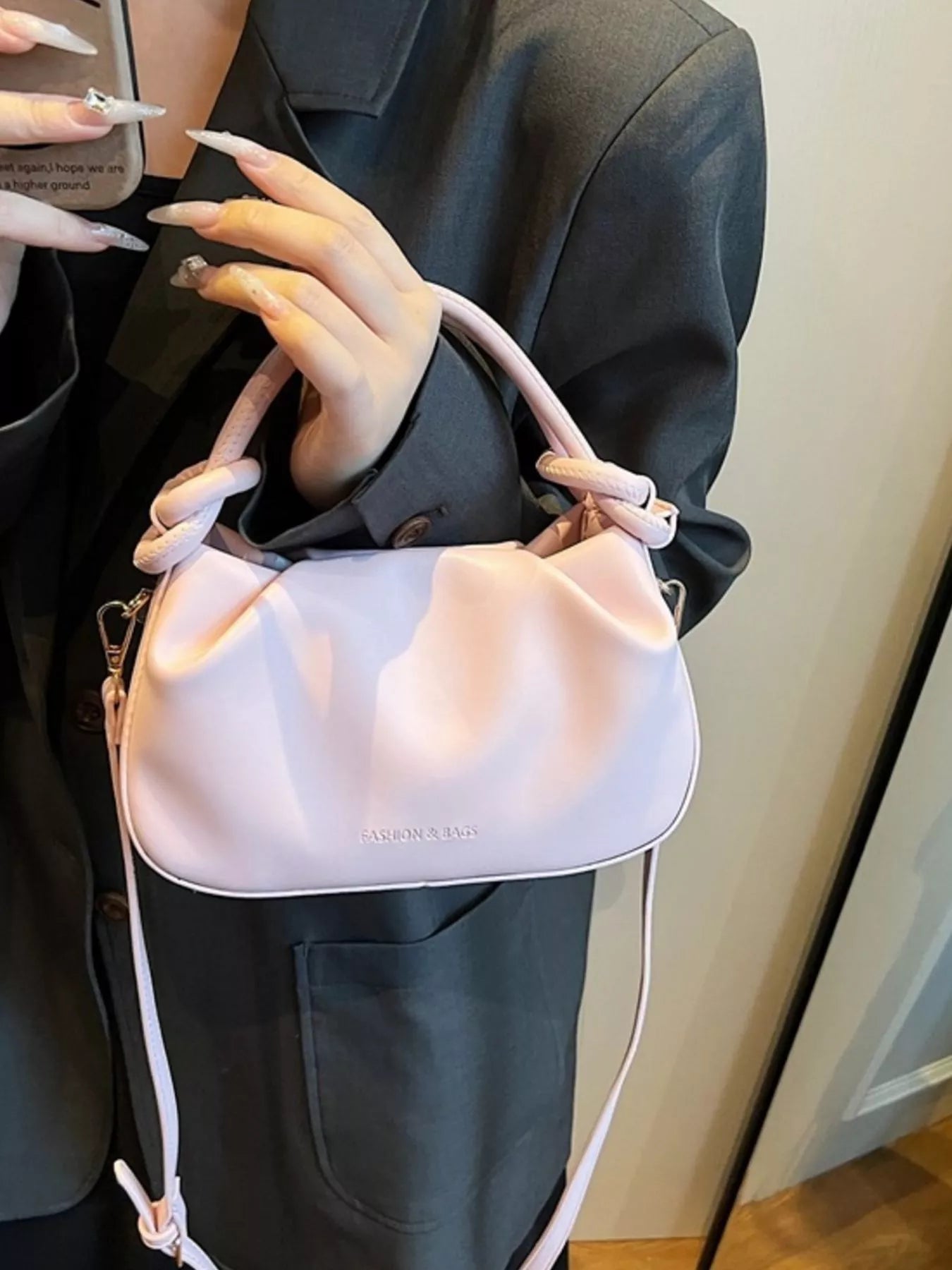 Person holding a pink handbag with a white strap indoors