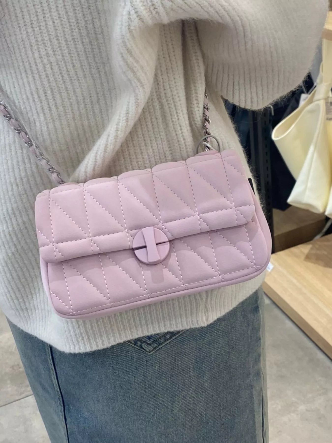 Pink quilted handbag worn over a shoulder with a neutral background