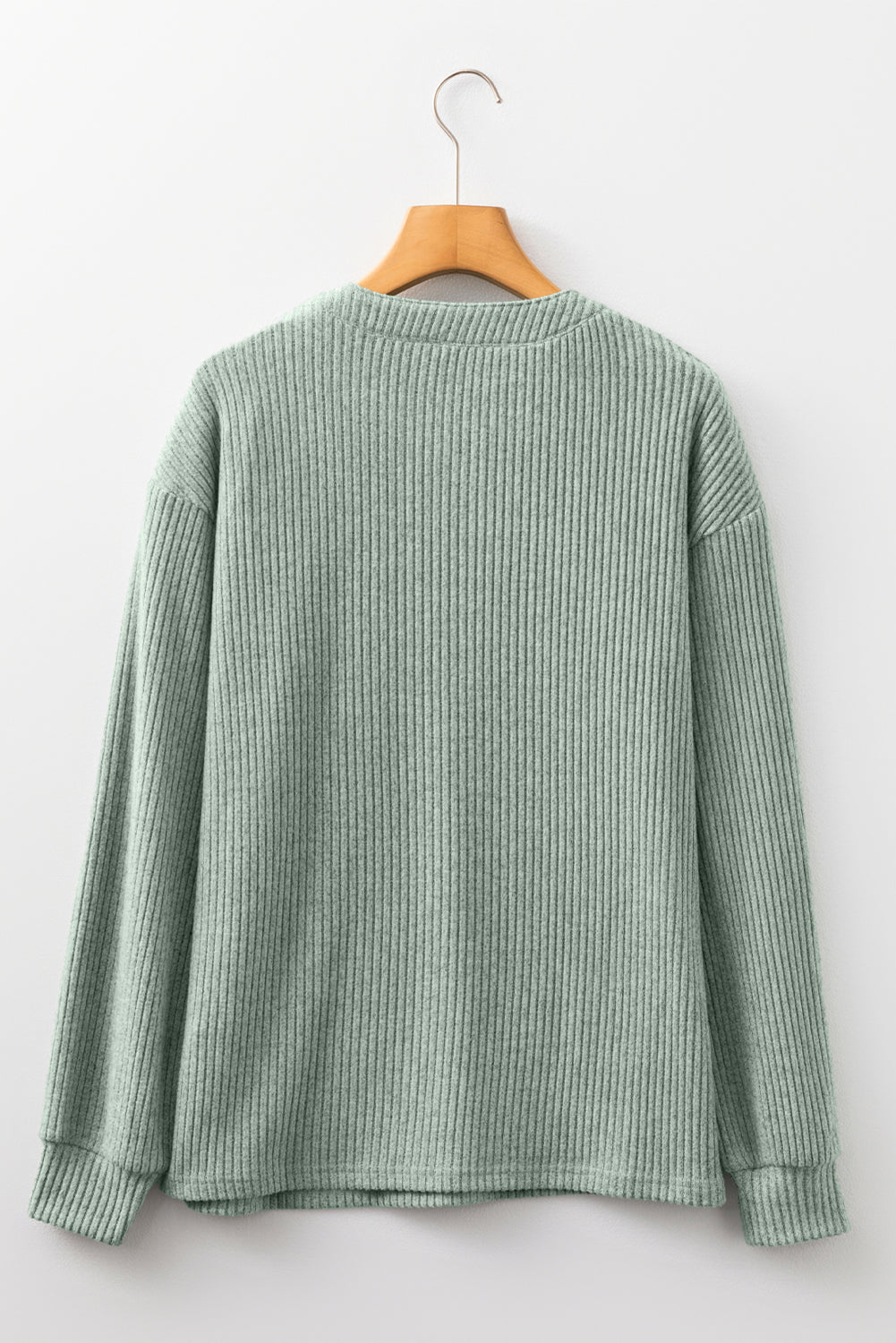 Green and gray striped shirt on a hanger against a white background