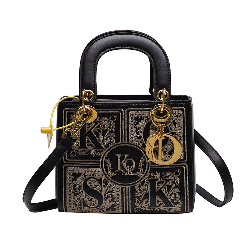 Black handbag with gold accents and decorative elements on a white background