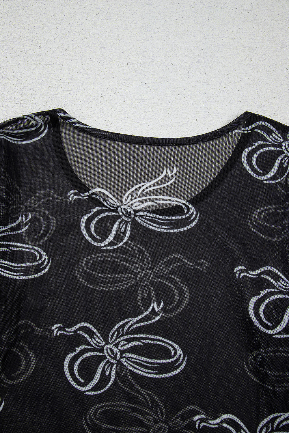 Black top with white bow pattern on a plain background