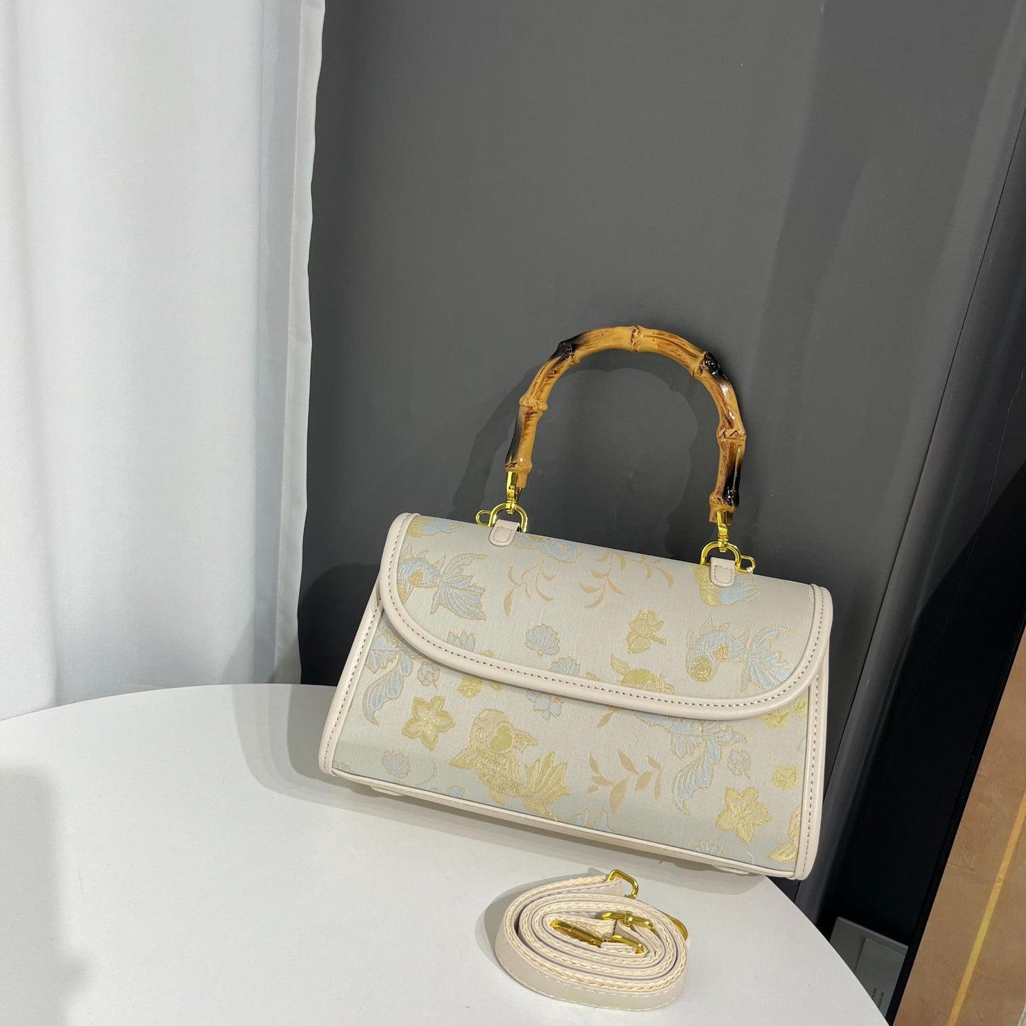 Floral embroidered handbag with gold accents on a white surface