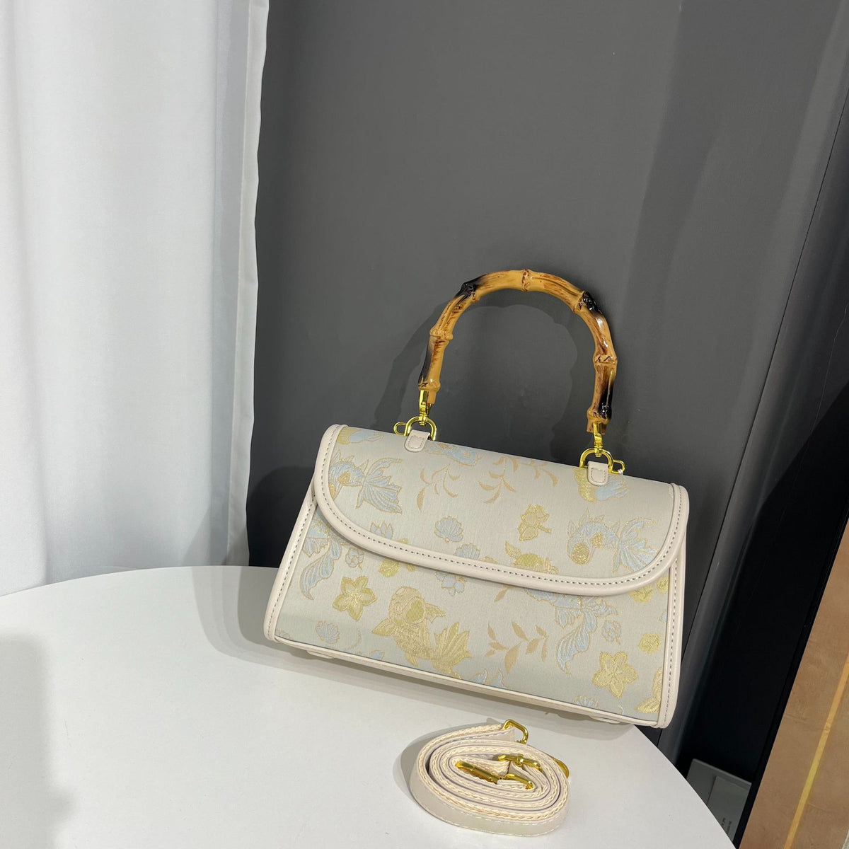 Floral embroidered handbag with gold accents on a white surface