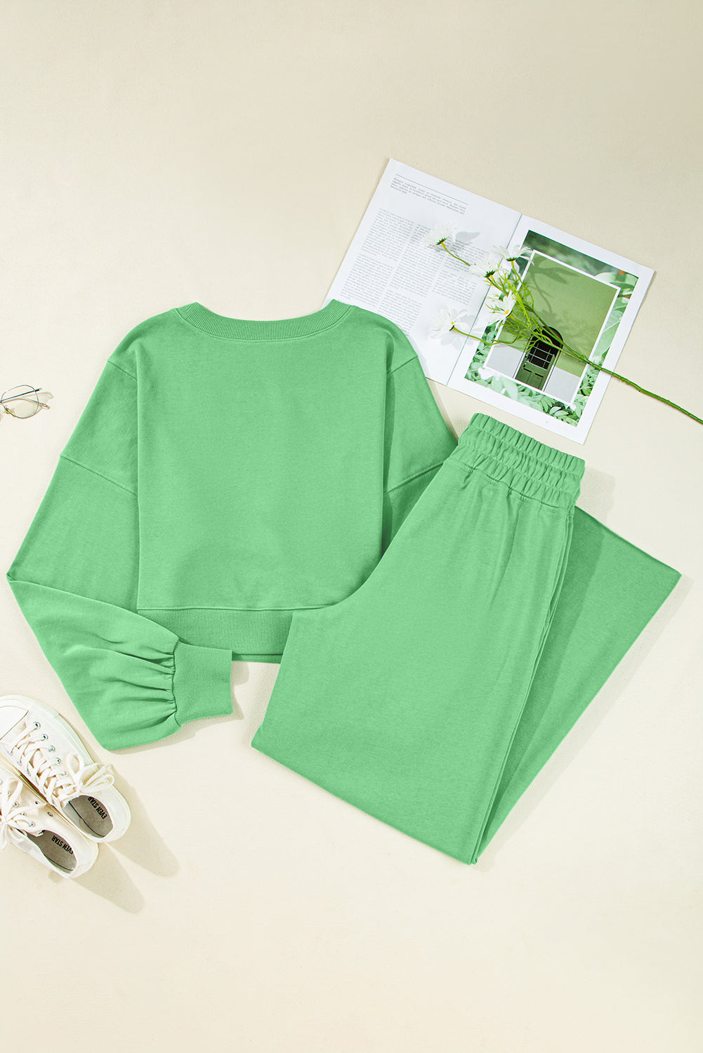Green pajama set on a light beige surface with a magazine in the background.