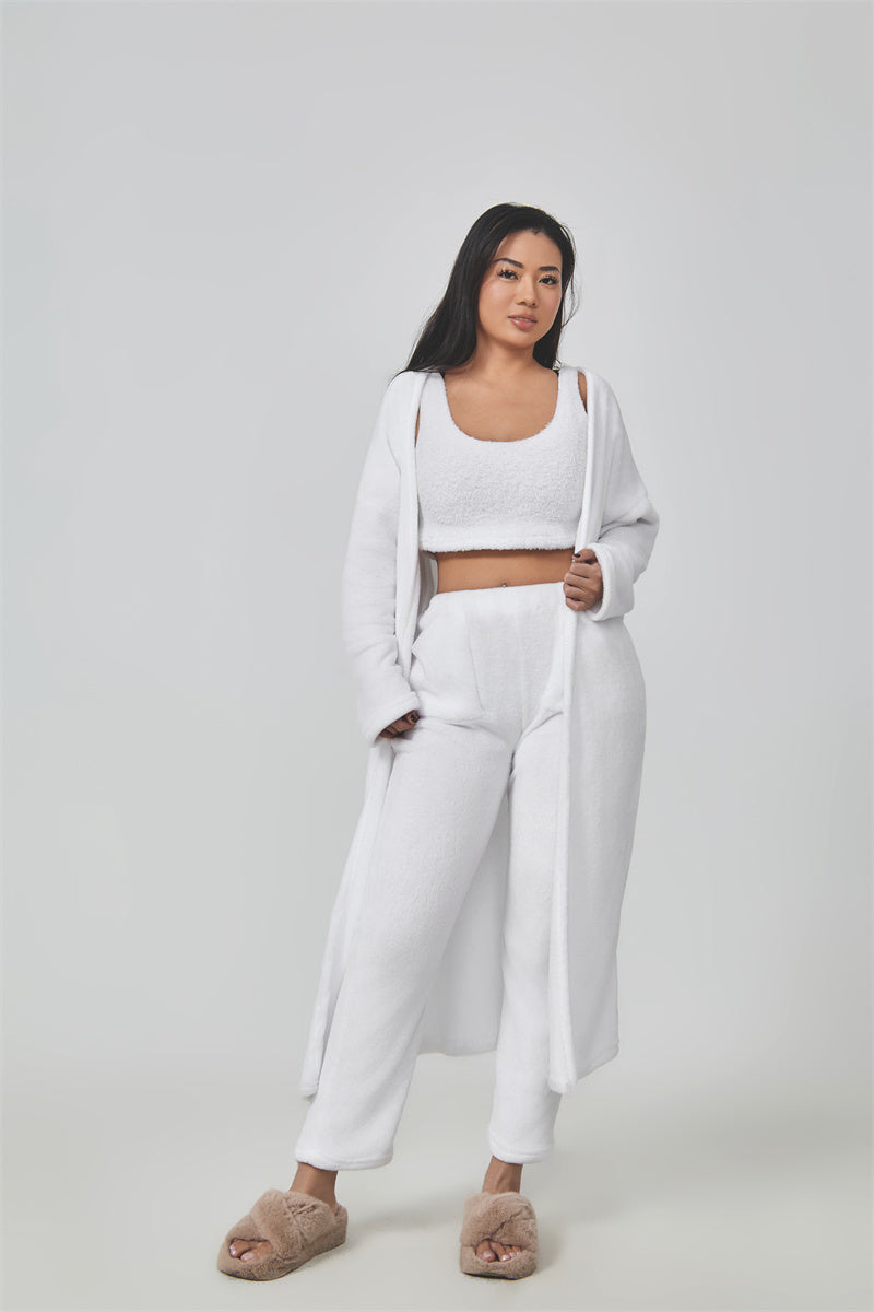 Woman wearing a white outfit with a long cardigan on a plain background