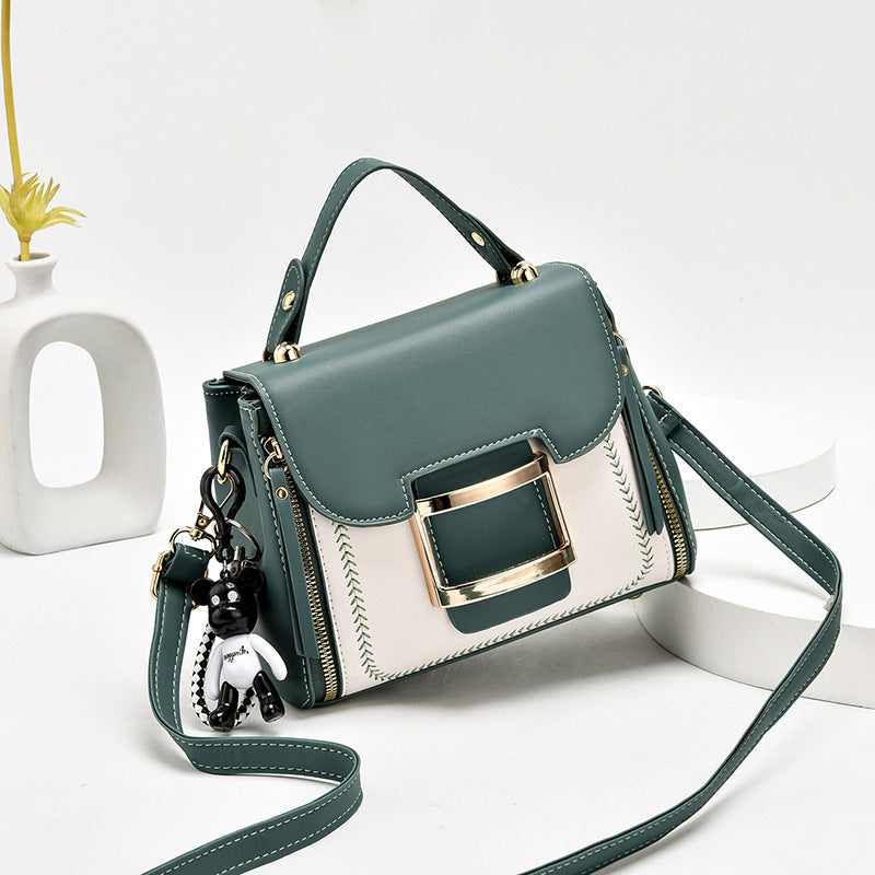 Green and white handbag with a gold buckle on a light gray background