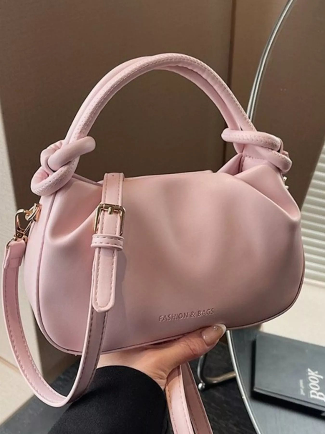 Pink handbag held by a person with a blurred background