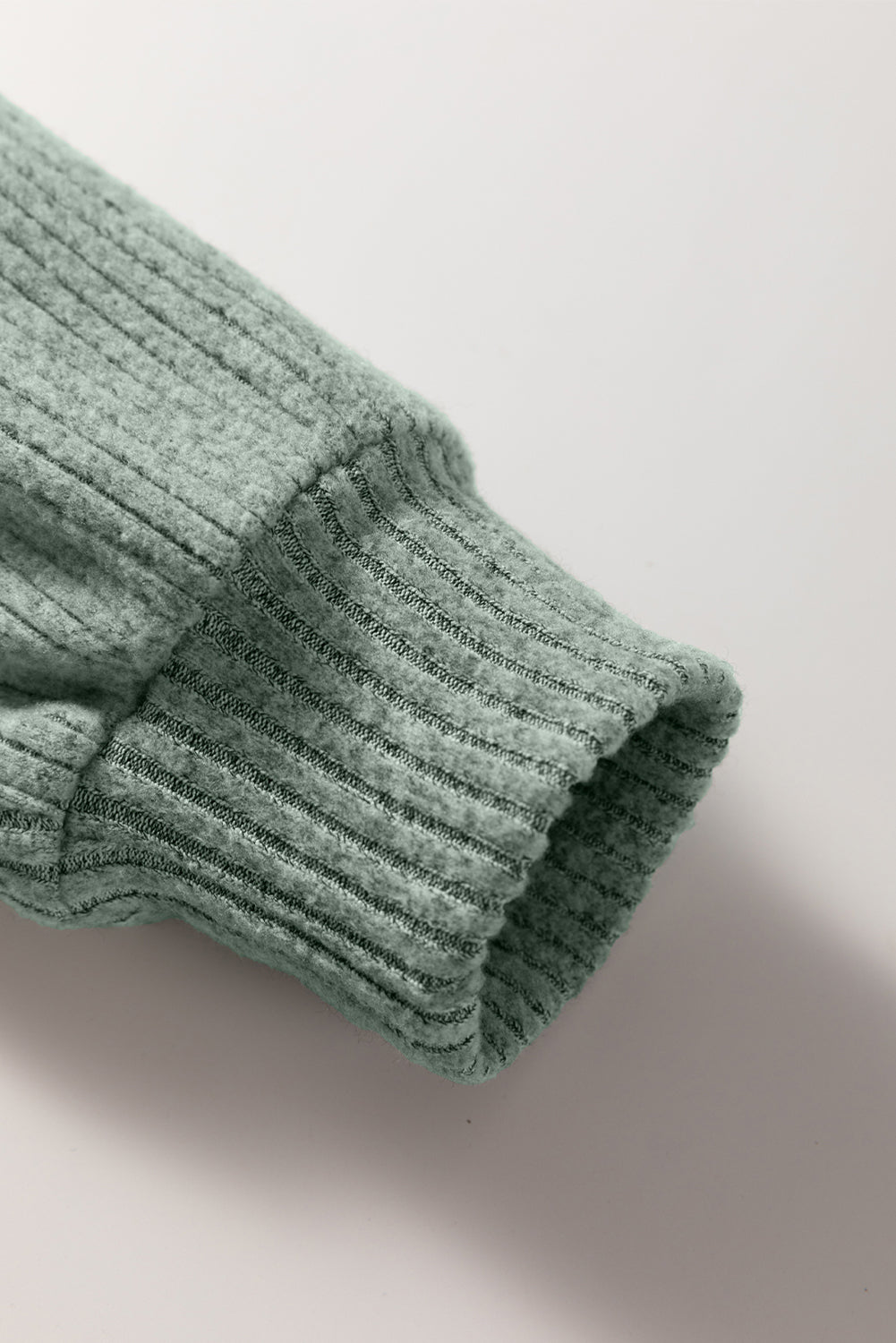 Close-up of a ribbed green fabric texture on a light background