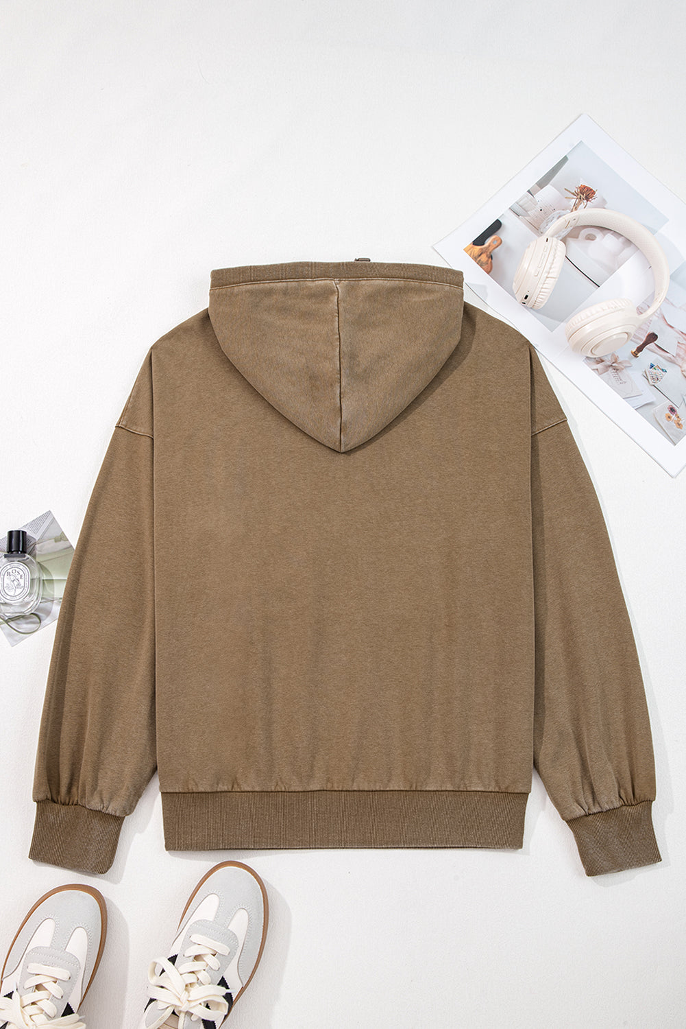 Brown hoodie on a white background with sneakers and a magazine.