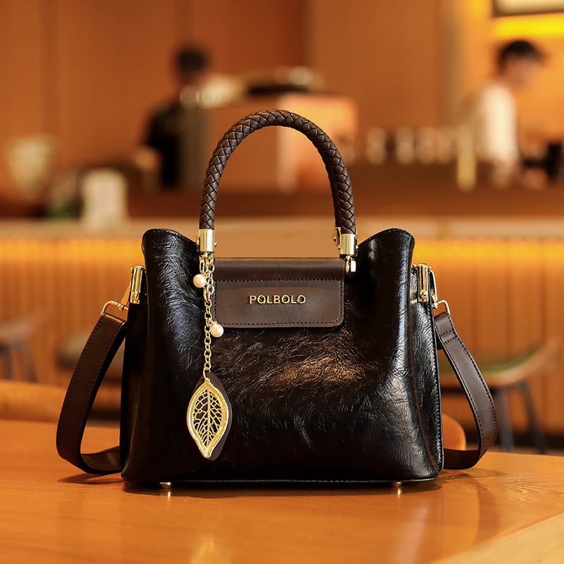 Black handbag with gold accents on a wooden surface, blurred indoor background