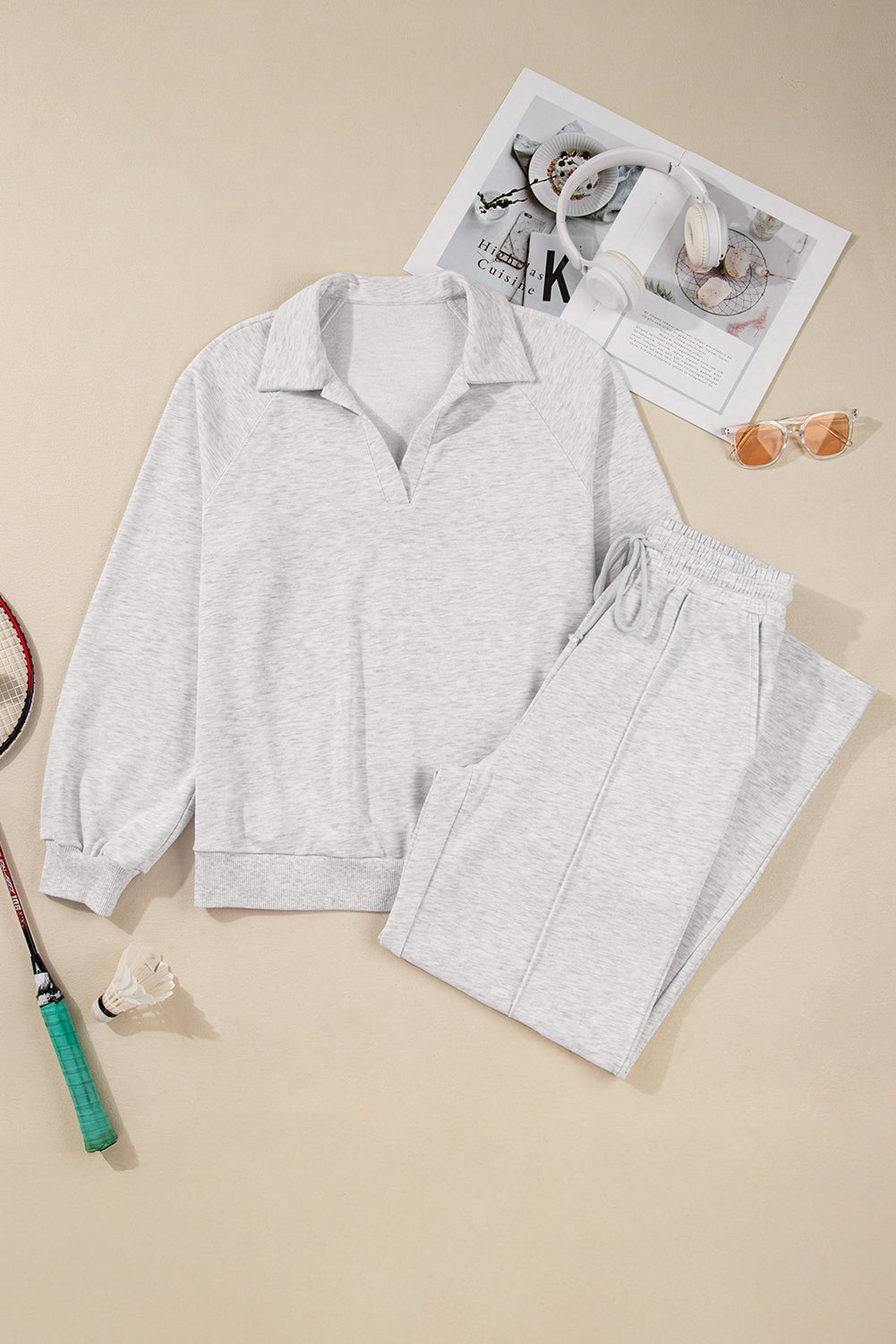 Gray tracksuit with a magazine and sunglasses on a beige background