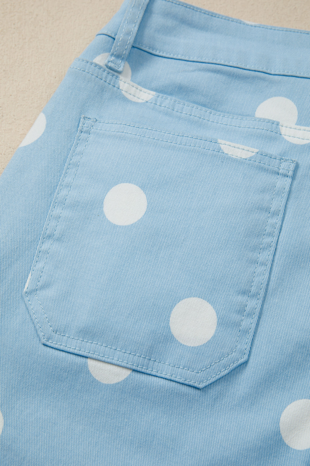 Close-up of a blue jeans with white polka dots on a beige background back view