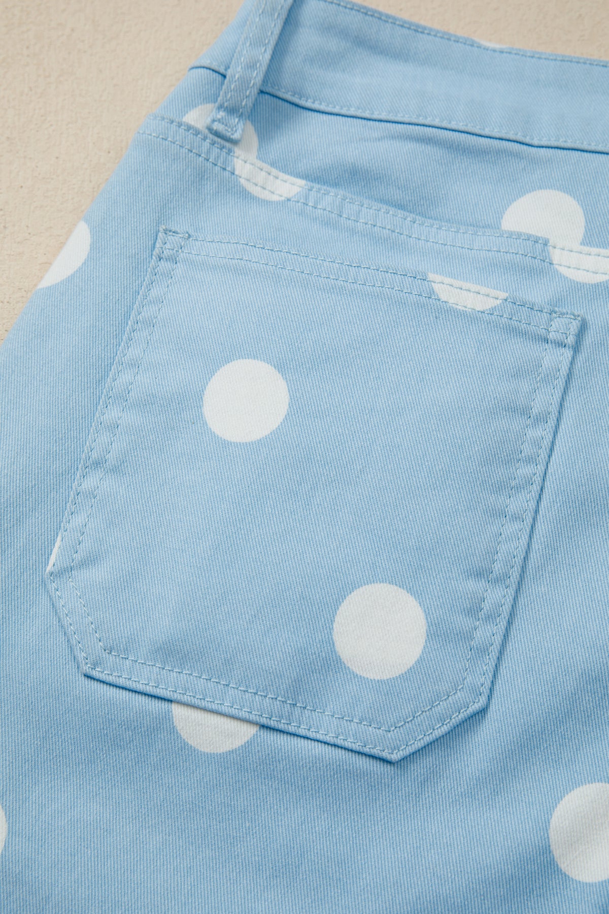 Close-up of a blue jeans with white polka dots on a beige background back view