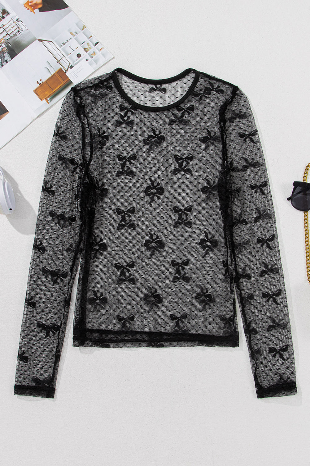 Full front view of a sheer black lace blouse with long sleeves and a bow design