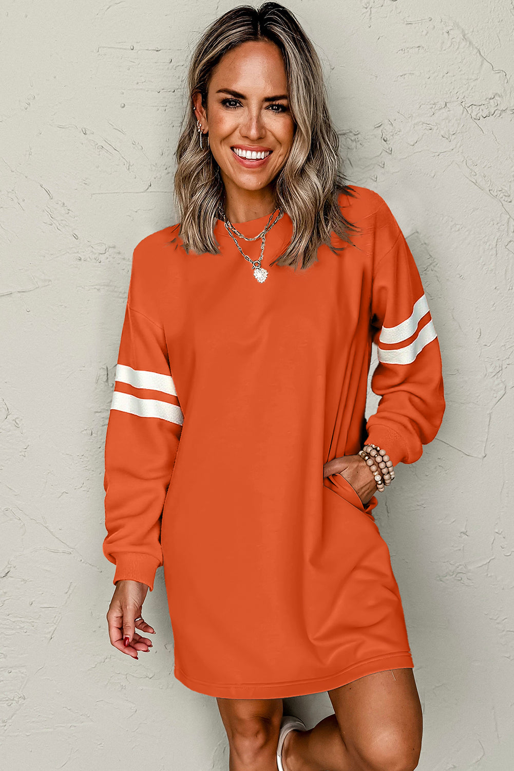 Smiling model wearing an orange colorblock athletic dress with white stripes, 