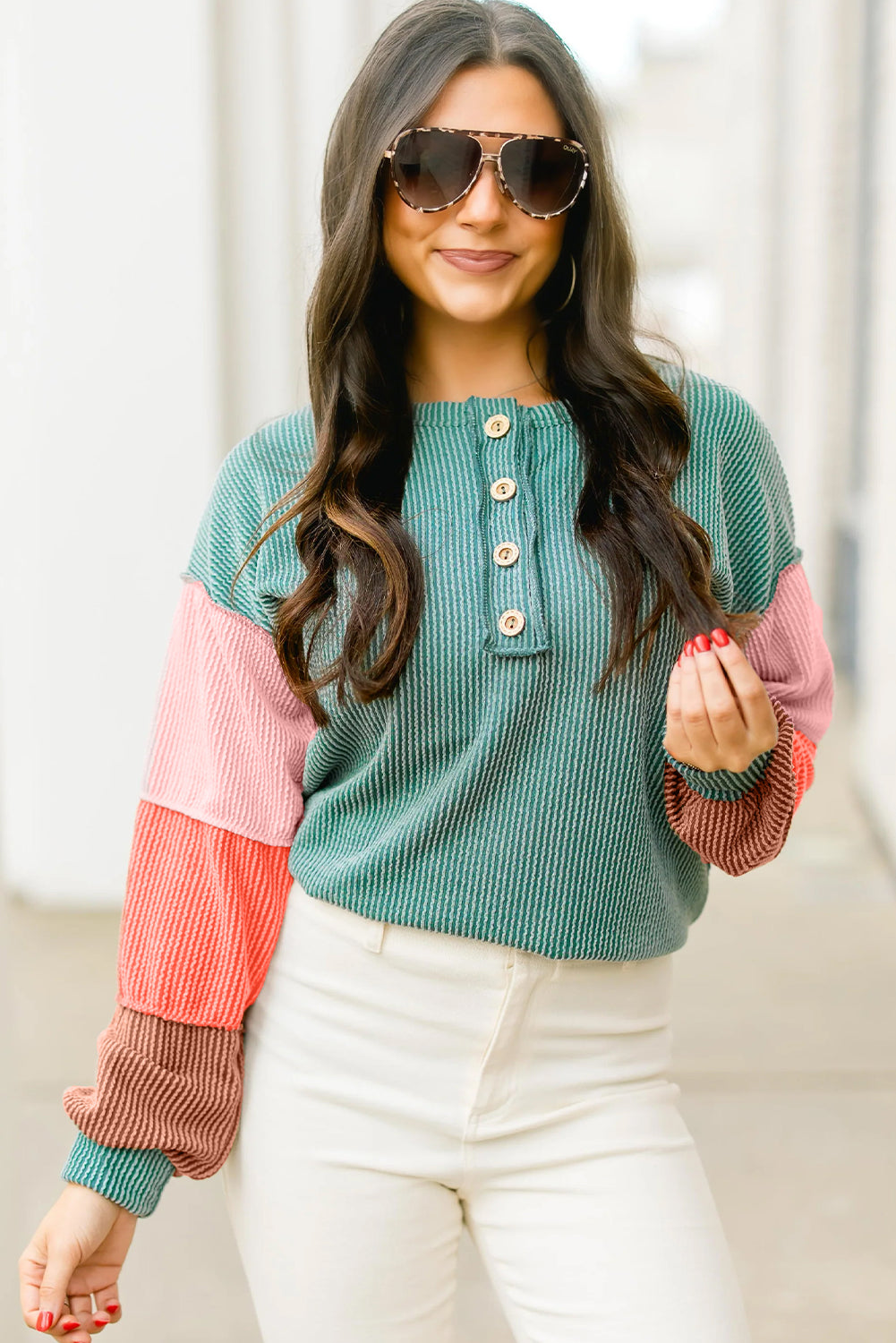 Model showcasing the vibrant colorblock design of a button-up top in a street setting, wearing sunglasses and a confident smile