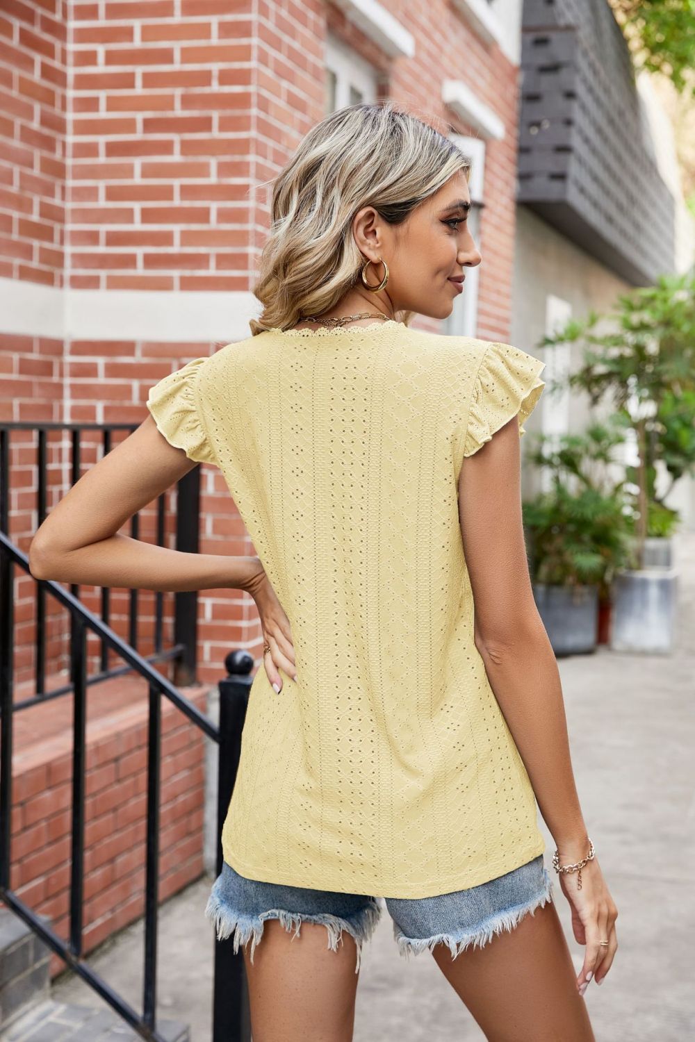 Back view of a Model wearing a Banana Yellow Ladies Eyelet Flutter Sleeve Scalloped V-Neck Top